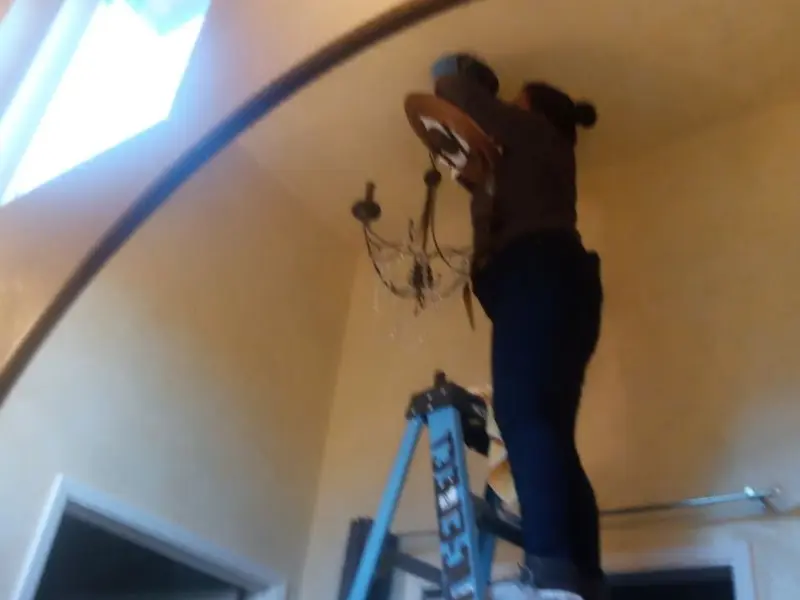 Electrician installing a chandelier in a Forks residence